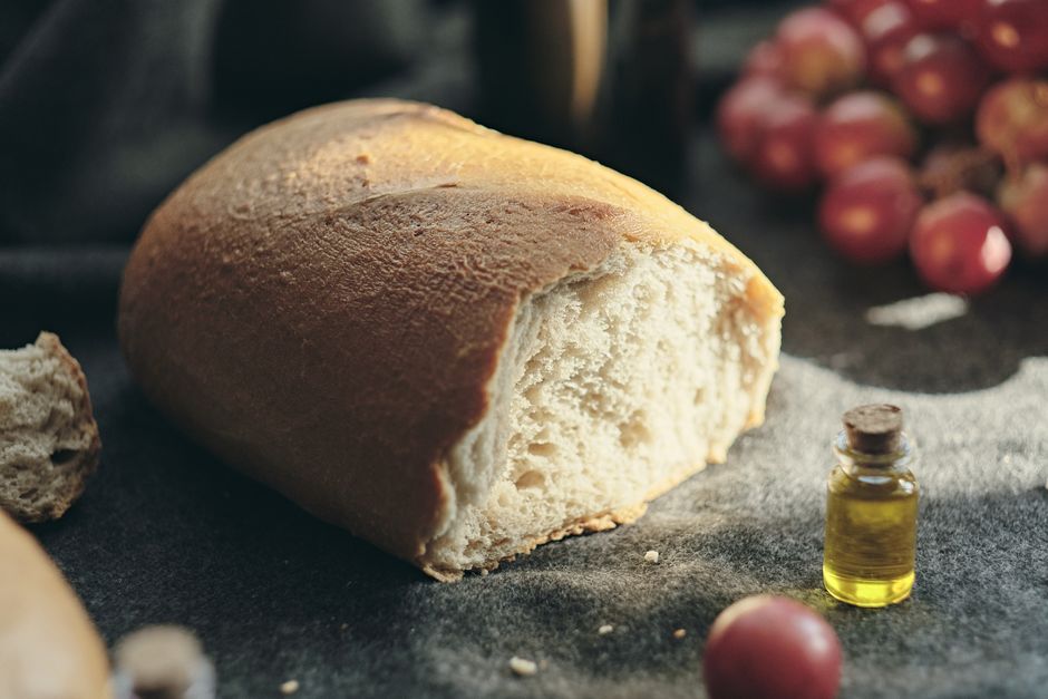 Un primer plano de pan recién horneado sobre tela, acompañado de uvas y aceite de oliva.