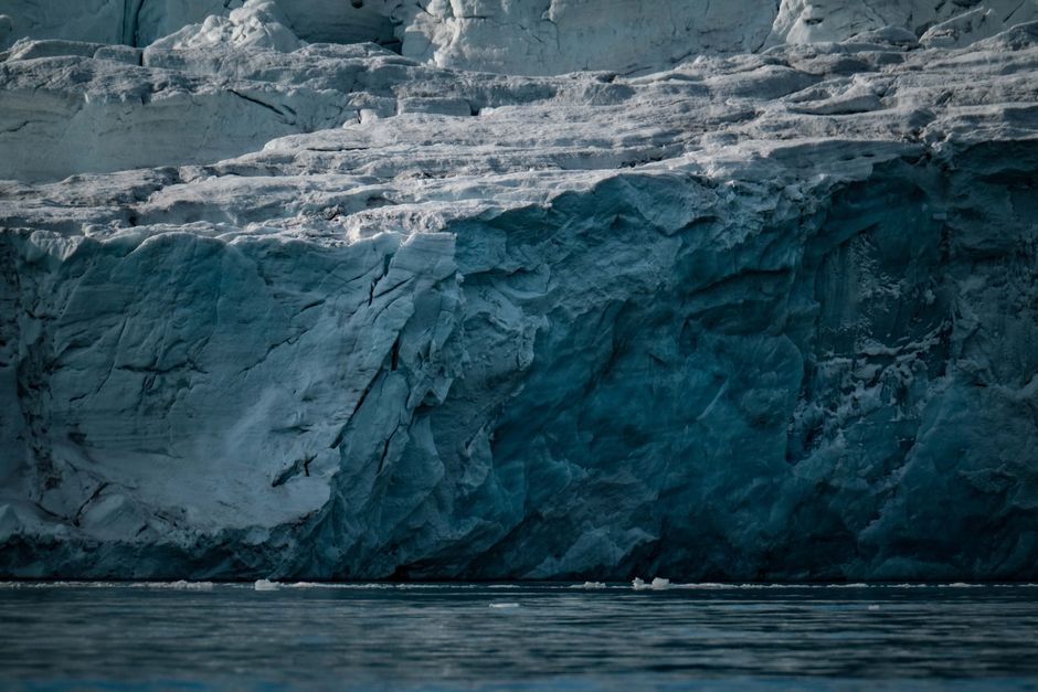 Una vista detallada de una enorme pared de iceberg en las tranquilas aguas del Ártico, que muestra la grandeza de las formaciones de hielo de la naturaleza.