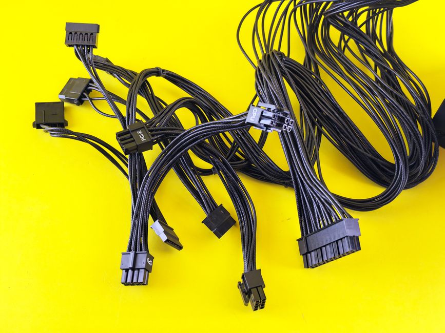 Cables de computadora negros esparcidos sobre una superficie de color amarillo vibrante, resaltando temas de conexión tecnológica.