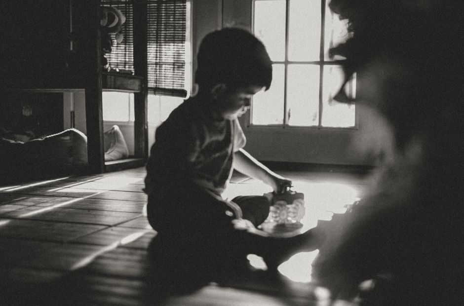 Un niño juega tranquilamente junto a una ventana, capturado en una silueta suave y con luz natural.