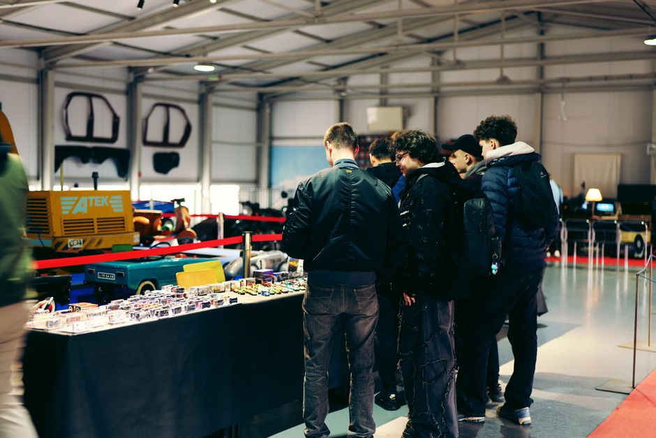 Los asistentes exploran maquetas de coches en miniatura en una exposición automovilística cubierta.