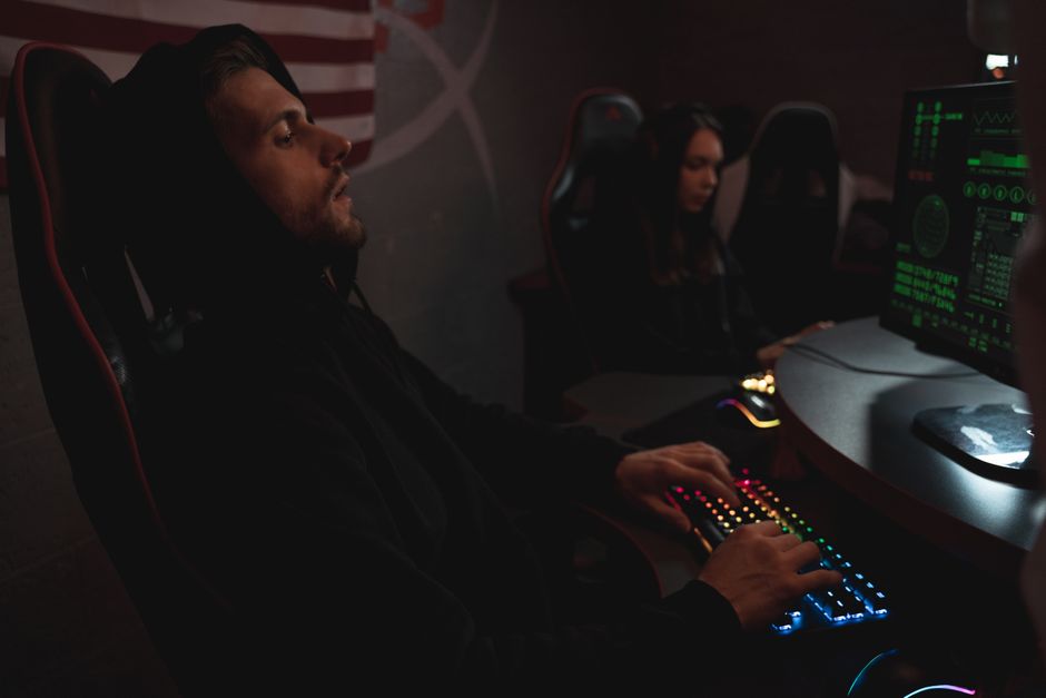 Jóvenes trabajando en tareas de ciberseguridad en un entorno tecnológico poco iluminado.