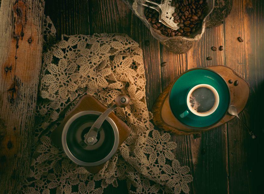 Vista desde arriba de una configuración de café vintage con molinillo y taza sobre una superficie de madera.