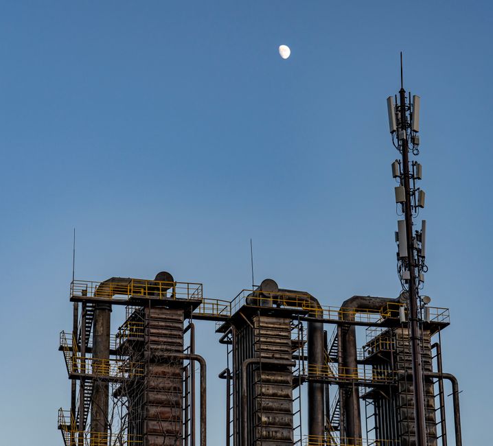 Vista en ángulo bajo de una fábrica industrial contra un cielo azul claro con la luna visible.