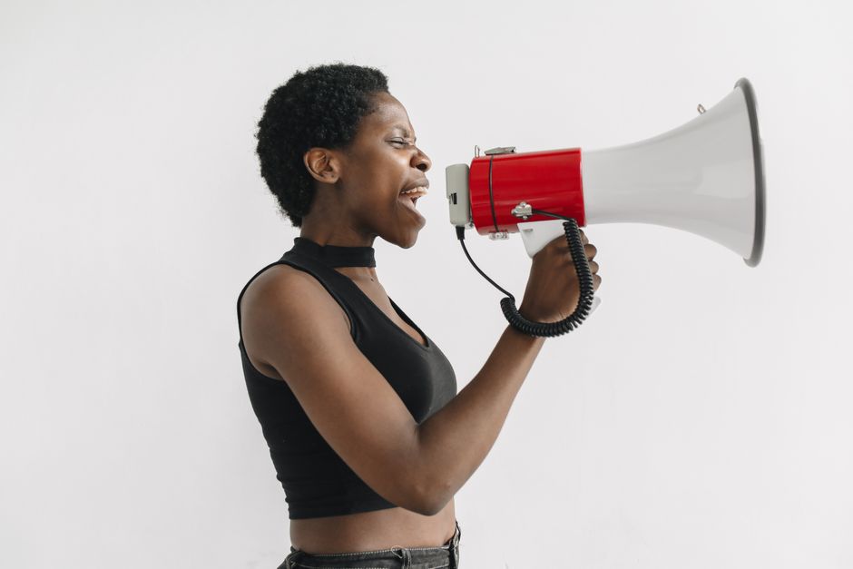 Mujer afroamericana usando un megáfono para protestar, simbolizando el activismo y el empoderamiento.