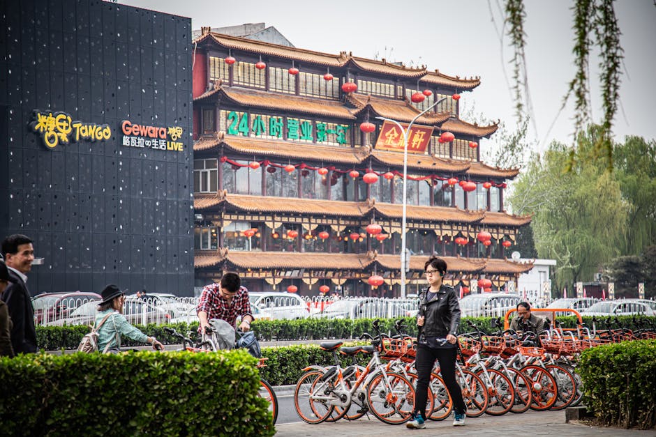 Una bulliciosa escena callejera de Beijing con arquitectura tradicional, bicicletas y faroles rojos que crean un encanto urbano.