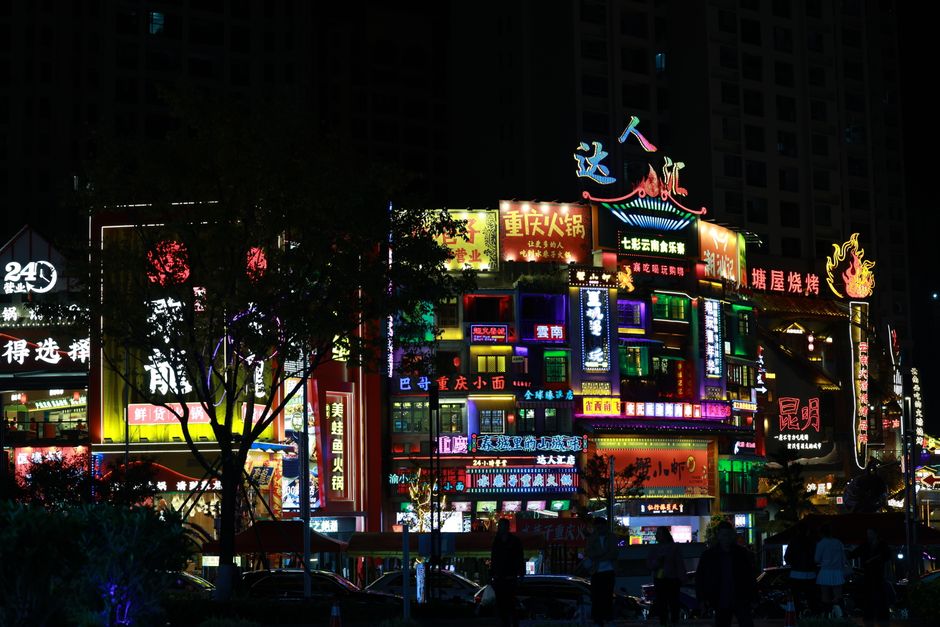Carteles de neón coloridos iluminan la bulliciosa calle nocturna en una ciudad asiática, mostrando una vida nocturna animada.