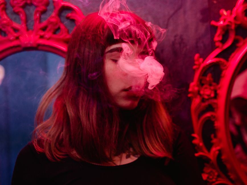 Una mujer envuelta en humo con luz roja en un ambiente vintage.