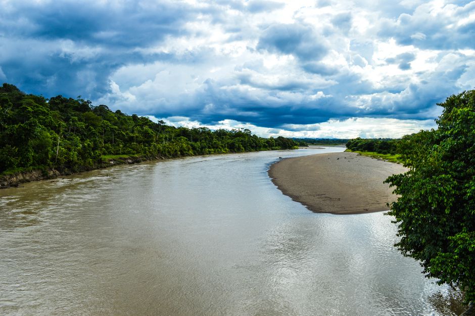 Un paisaje vibrante de un río serpenteando a través de un exuberante greenery bajo cielos dramáticos en Puerto Nuevo, Chocó, Colombia.