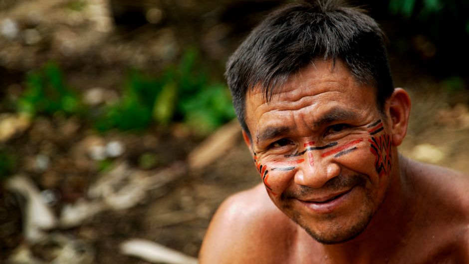 Retrato de un hombre indígena en la Amazonía, mostrando pintura facial tradicional.