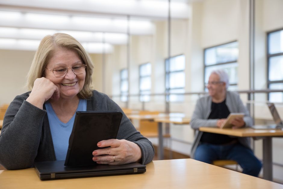 Adultos mayores aprendiendo a usar tabletas en una aula moderna en Portugal.