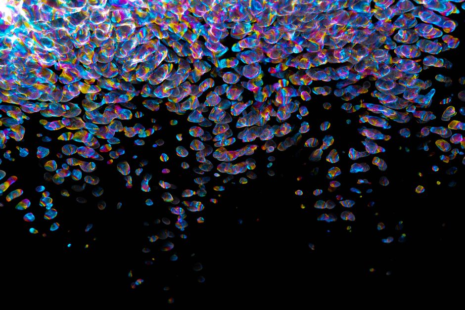 Patrón abstracto colorido con reflexiones de luz de arcoíris sobre un fondo negro.