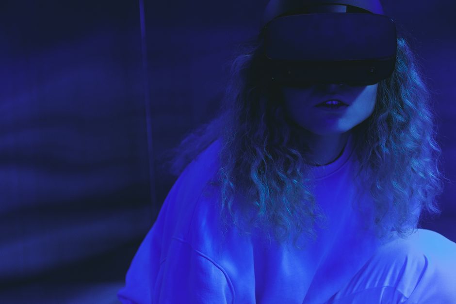 Una mujer con un visor de VR disfruta de una experiencia de realidad virtual bajo iluminación de neón.