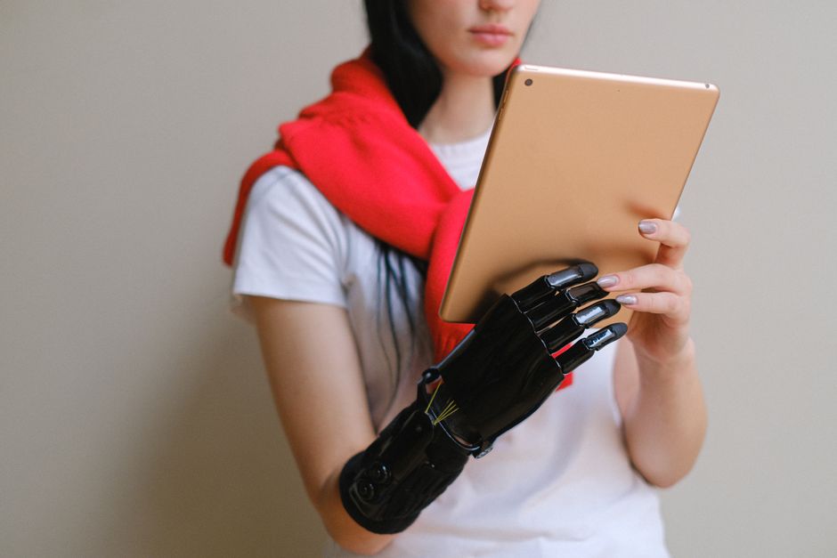 Una mujer con un brazo prostético biónico utiliza una tableta digital en interiores.