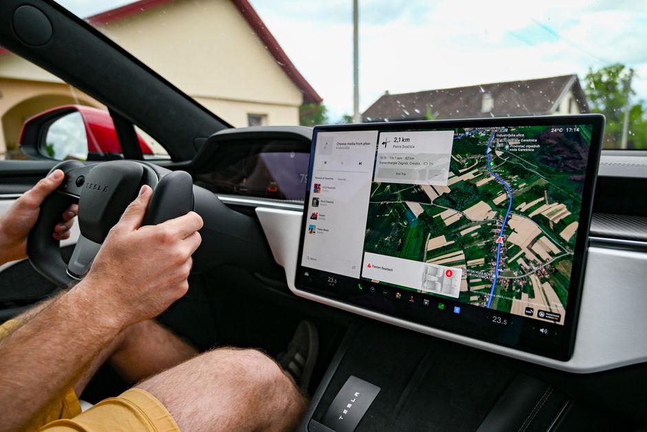 Hombre conduciendo un Tesla usando GPS en el panel táctil para navegación.