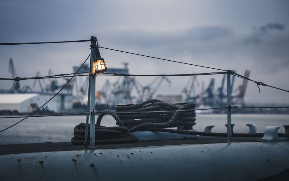 Una vista serena del puerto industrial de Gdynia al anochecer, con cuerdas y grúas bajo un cielo nublado.