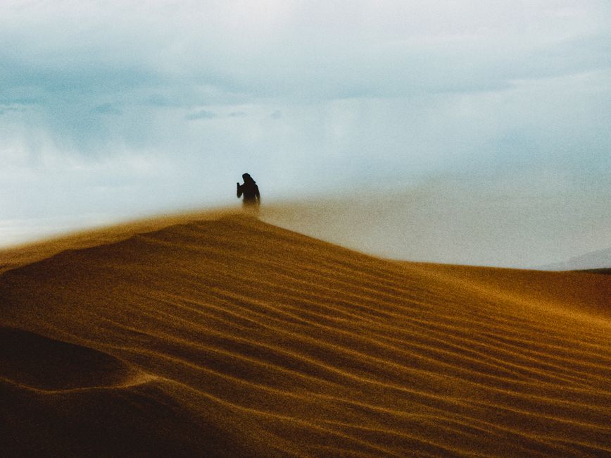 Silueta de una persona sobre las dunas de arena del Sáhara argelino al atardecer, que captura la aventura y la serenidad.