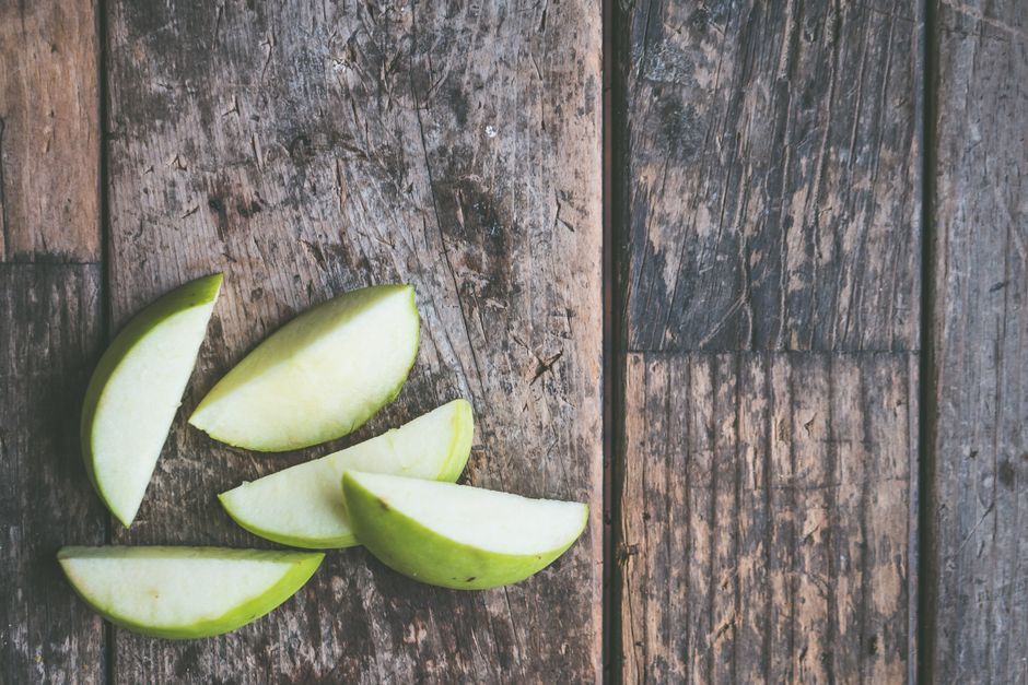 Manzanas verdes cortadas colocadas sobre una superficie de madera rústica, perfectas para temas de comida natural.