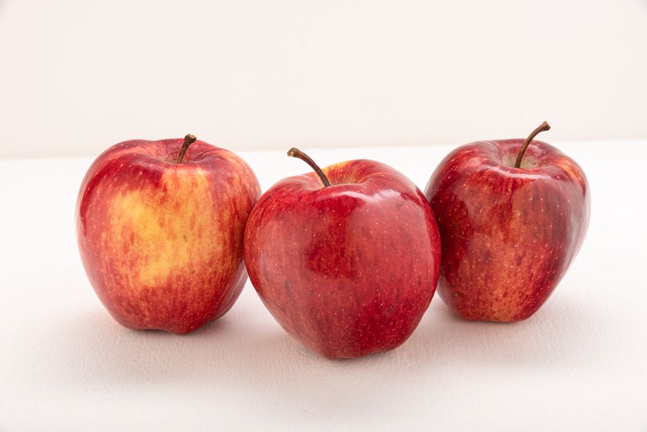 Imagen de alta calidad de tres manzanas rojas frescas contra un fondo blanco.
