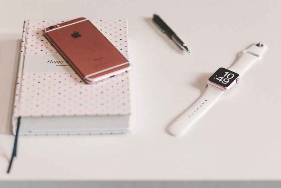 Una mesa minimalista con un smartwatch, smartphone, bolígrafo y cuaderno para profesionales apasionados por la tecnología.