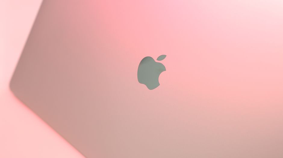 Imagen en primer plano de un portátil elegante sobre un fondo rosa suave, creando una estética moderna y minimalista.