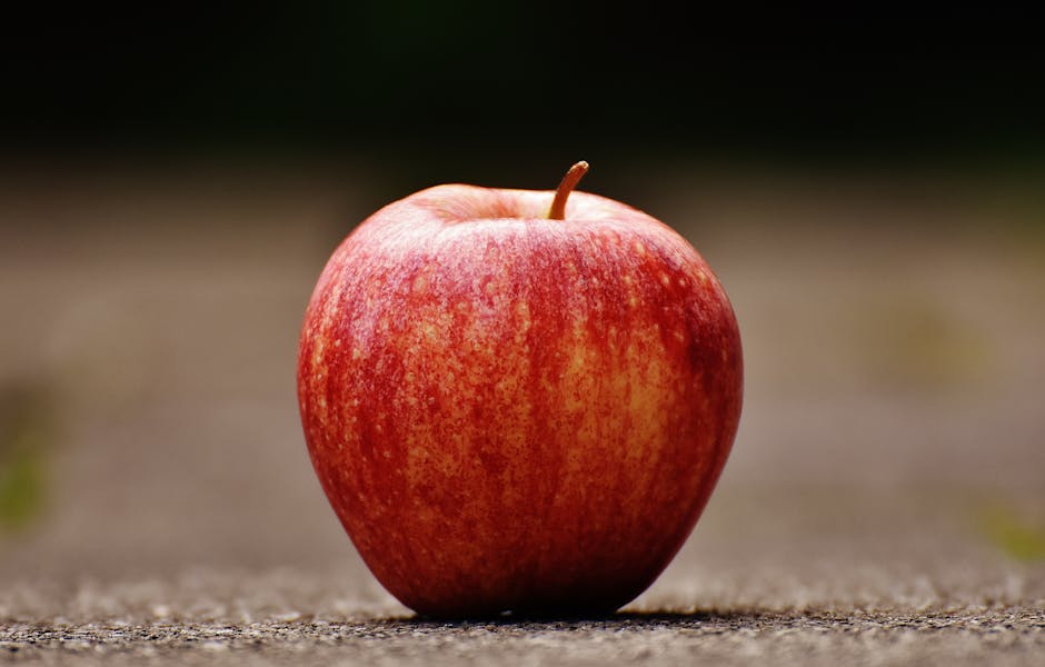 Fotografía De Enfoque Superficial De Manzana Roja Sobre Pavimento Gris