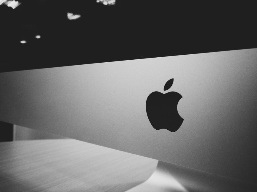 Primer plano de un logotipo de Apple en blanco y negro en una pantalla de escritorio con un diseño moderno y minimalista.