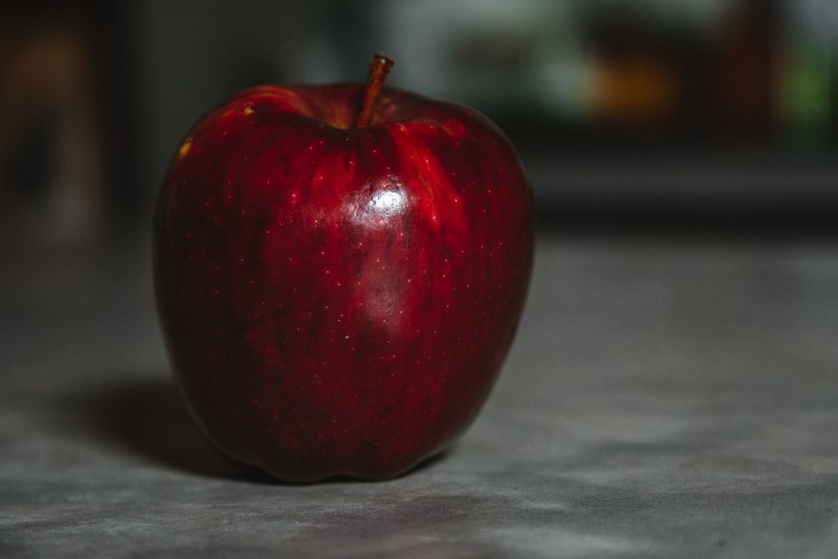 Una sola manzana roja en un primer plano sobre una superficie lisa, que exuda frescura.