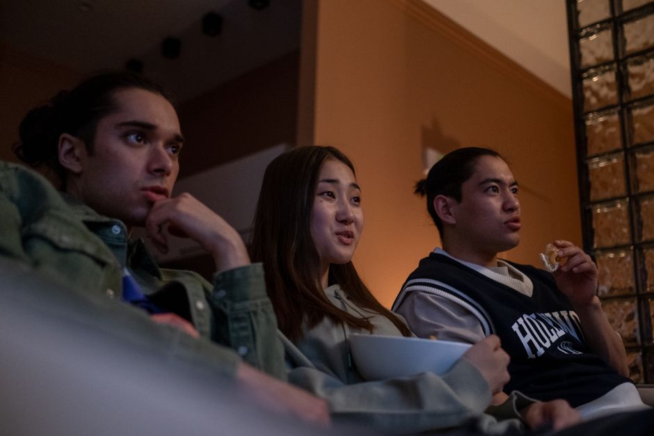 Tres adolescentes diversos viendo la televisión en interiores, compartiendo snacks y disfrutando de una acogedora noche de cine.