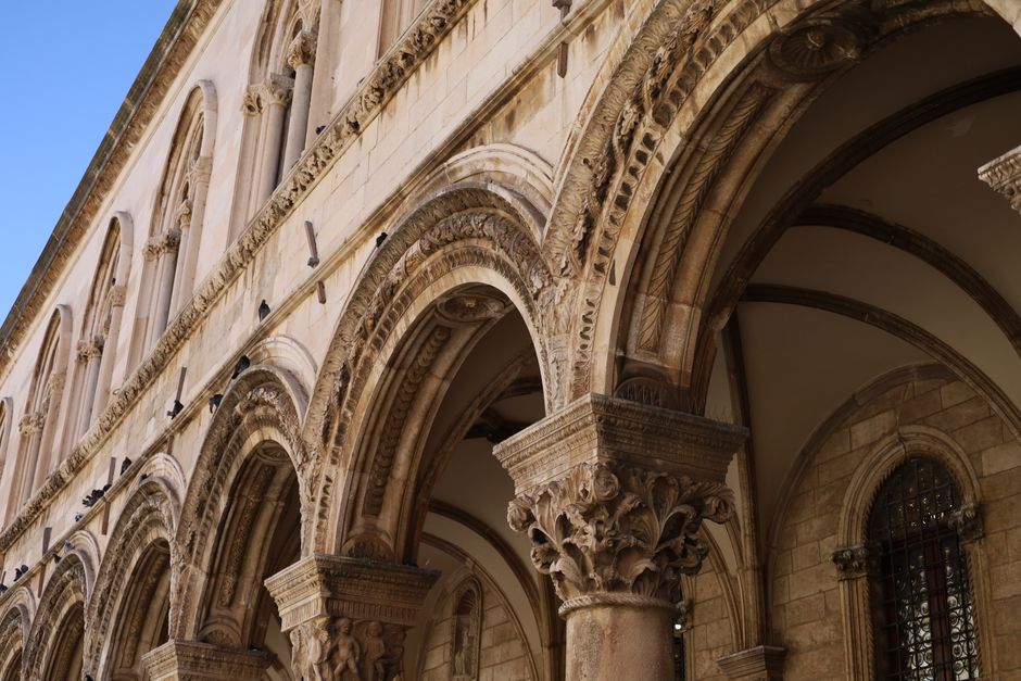 Primer plano de arcos de piedra ornamentados y columnas detalladas en la fachada de un edificio histórico.