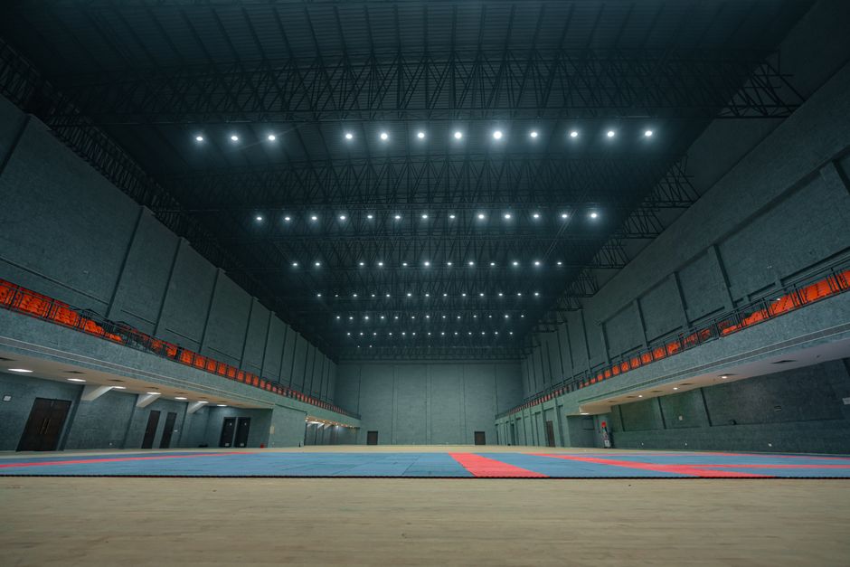 Amplio pabellón deportivo interior con luces brillantes en el techo y suelo vacío en Surat, India.