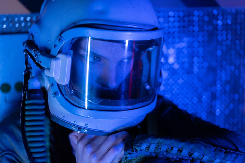 Una astronauta con casco y visor reflectante explora un ambiente espacial iluminado en azul.