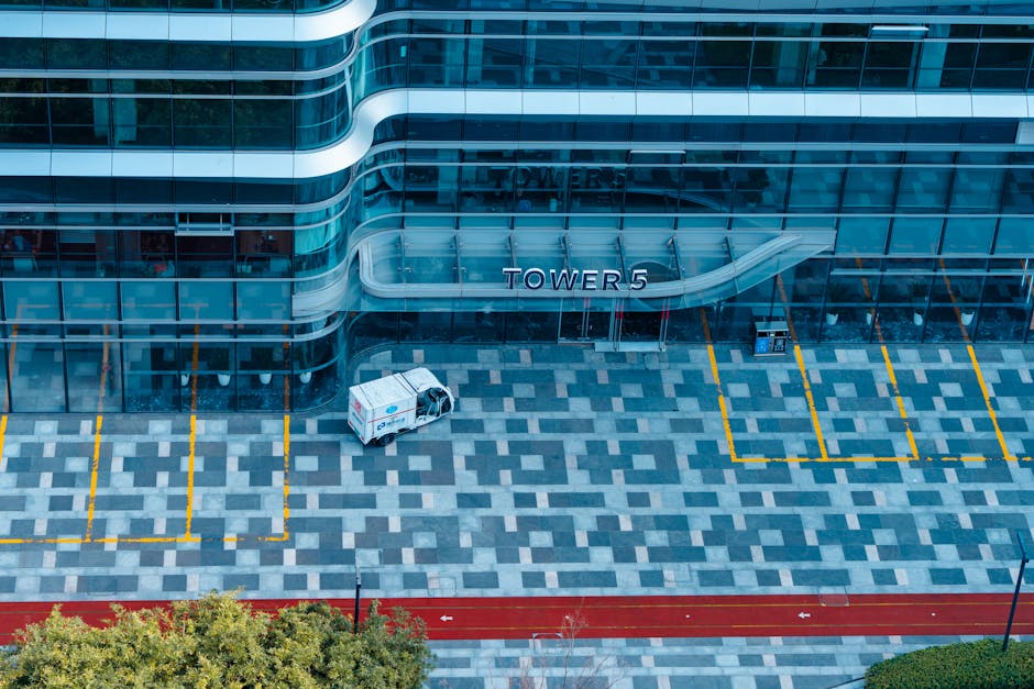 Vista aérea de la elegante fachada de cristal de la Torre 5 en Hangzhou, China, que incluye un aparcamiento de diseño geométrico.