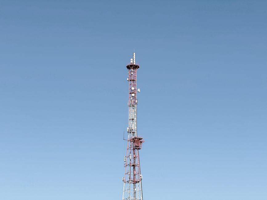 Una alta torre de comunicaciones contra un cielo azul sin nubes, que simboliza las telecomunicaciones modernas.