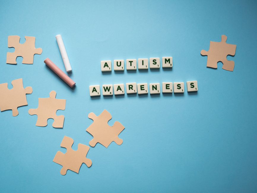 Concepto creativo de concienciación sobre el autismo con piezas de rompecabezas en un fondo azul.