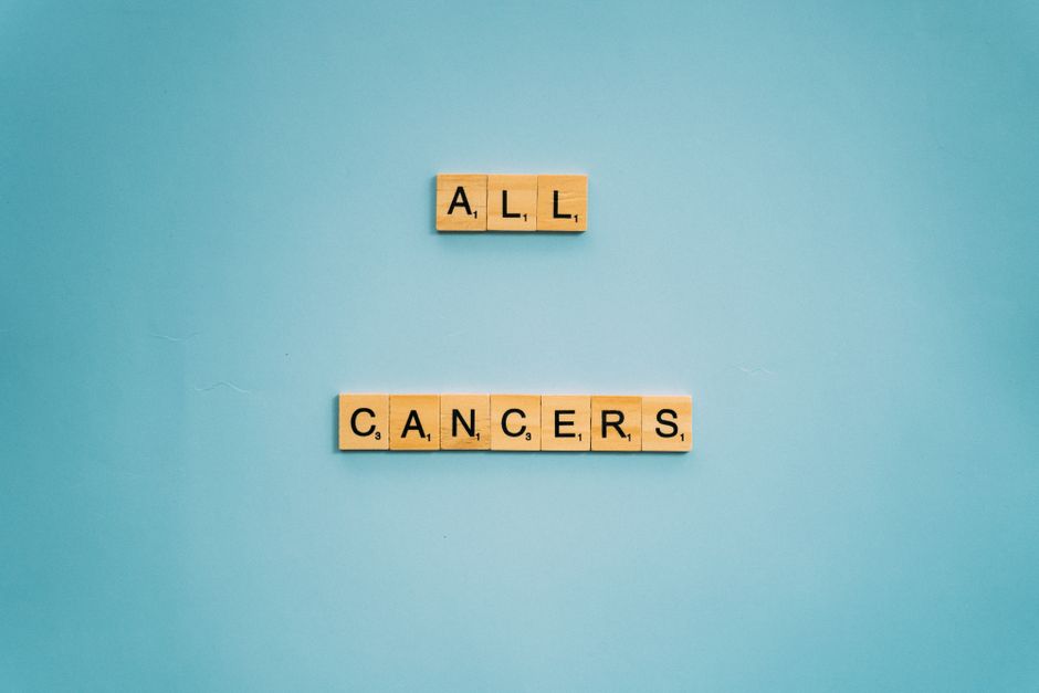 Fichas de Scrabble formando 'Todos los Cánceres' sobre un fondo azul claro, simbolizando la concienciación sobre el cáncer.