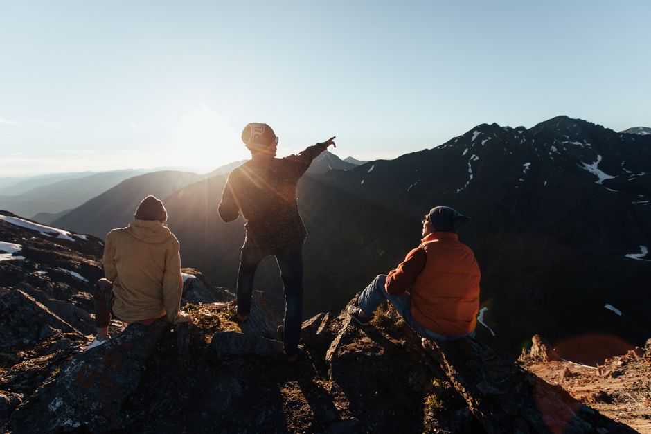 Tres adultos disfrutan de una vista escénica de la montaña al amanecer, capturando la esencia de la aventura al aire libre.