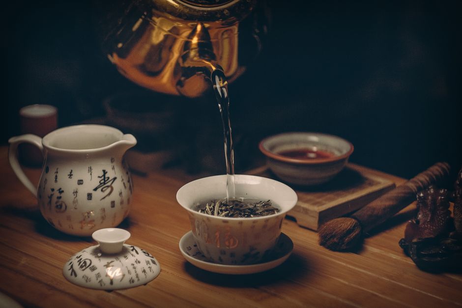 Representación artística de una ceremonia del té china tradicional con menaje de porcelana y vertido de agua caliente.
