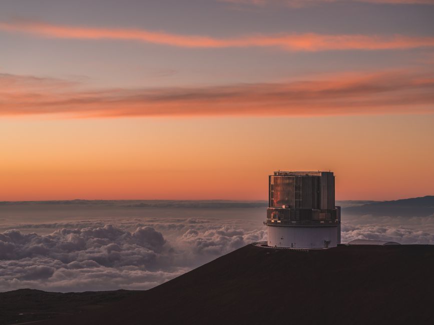Una vista impresionante del Observatorio Mauna Kea contra un vibrante cielo al atardecer en Hawái.