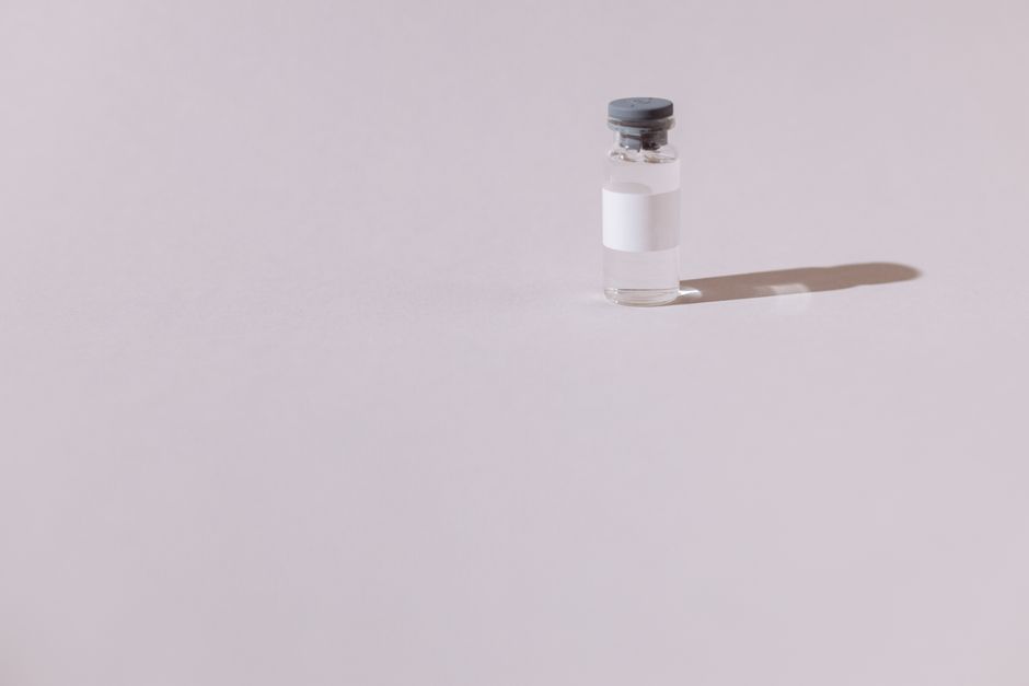 Un frasco de vacuna estéril aislado sobre un fondo gris minimalista, enfatizando la salud y la medicina.
