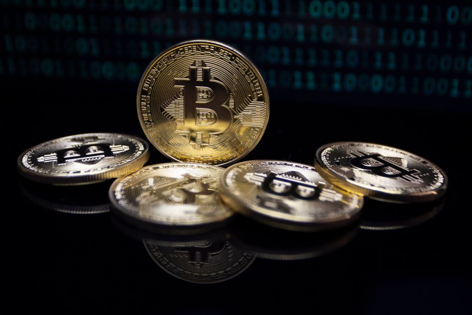 Acercamiento de monedas de Bitcoin de oro sobre un fondo de código binario digital, simbolizando finanzas modernas.