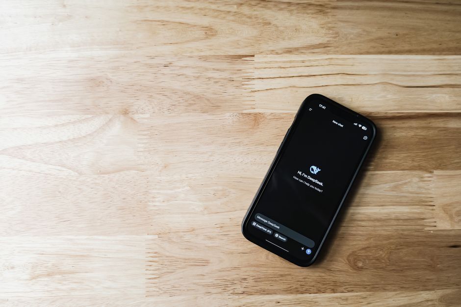 Vista de arriba hacia abajo de un teléfono inteligente que muestra una interfaz de chatbot en una superficie de madera clara.