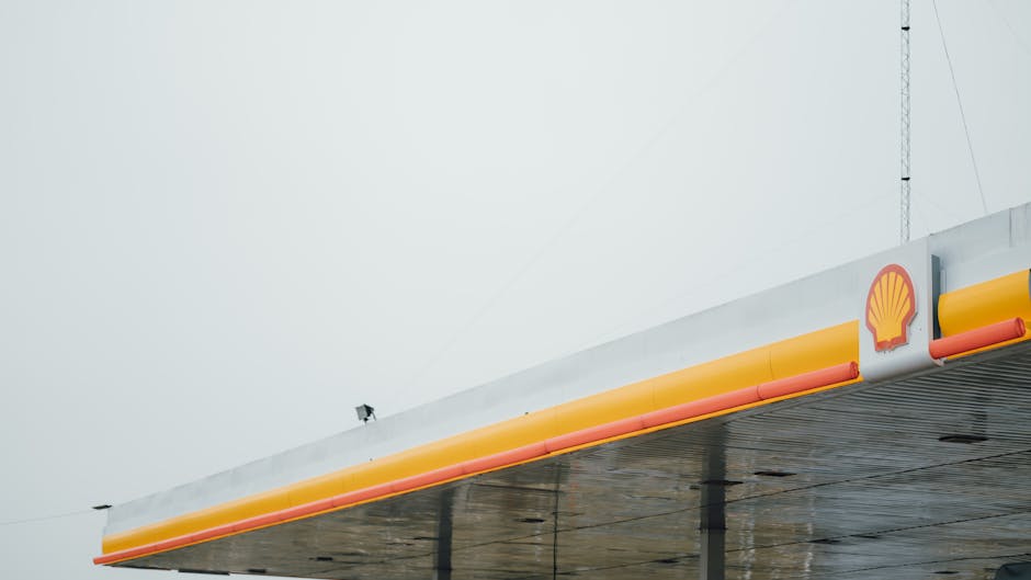 Vista minimalista del dosel de una gasolinera Shell contra un cielo nublado, enfatizando la simplicidad y la marca.