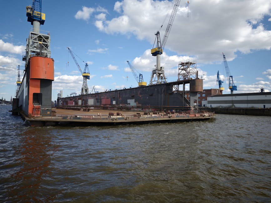 Un astillero con un barco atracado y varias grúas bajo un cielo azul brillante.