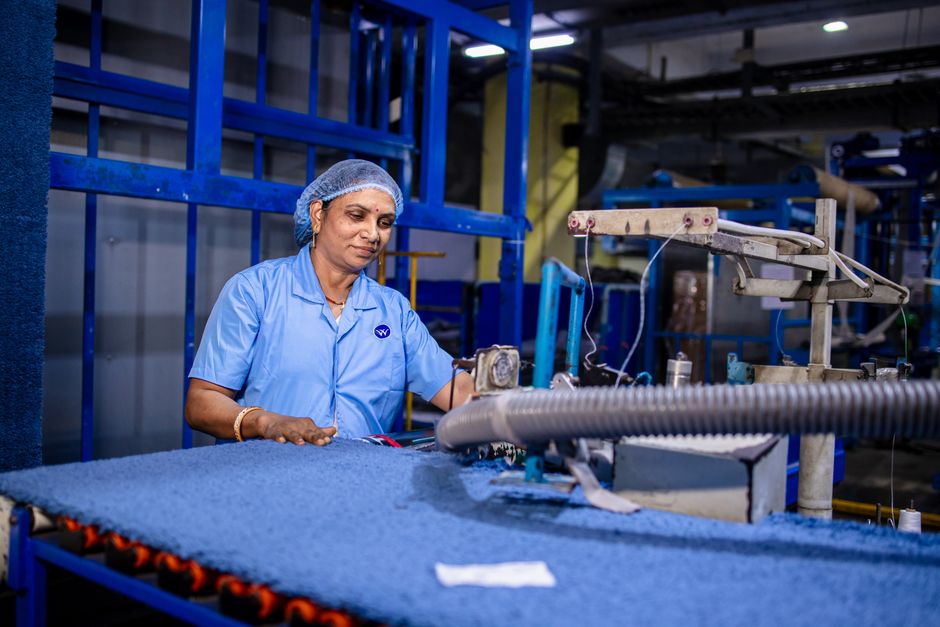 Trabajadora de fábrica opera maquinaria textil en interiores, mostrando dedicación y habilidad en un entorno industrial.