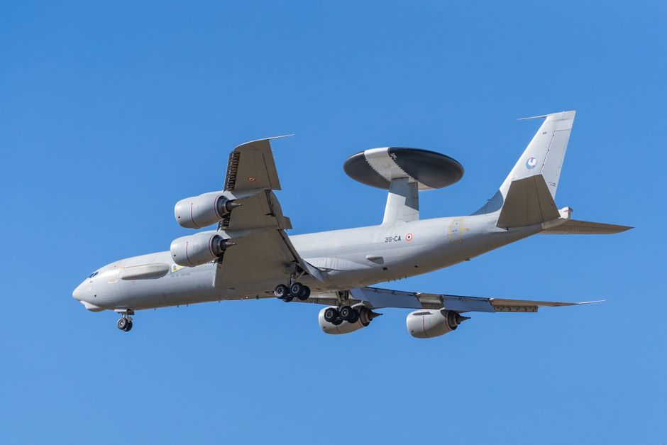 Un avión militar volando contra un cielo azul claro, mostrando sus potentes motores y su sistema de radar.