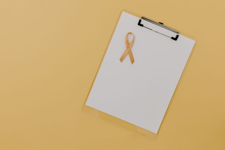 Imagen de una cinta de concienciación sobre el cáncer infantil en un portapapeles contra un fondo amarillo.