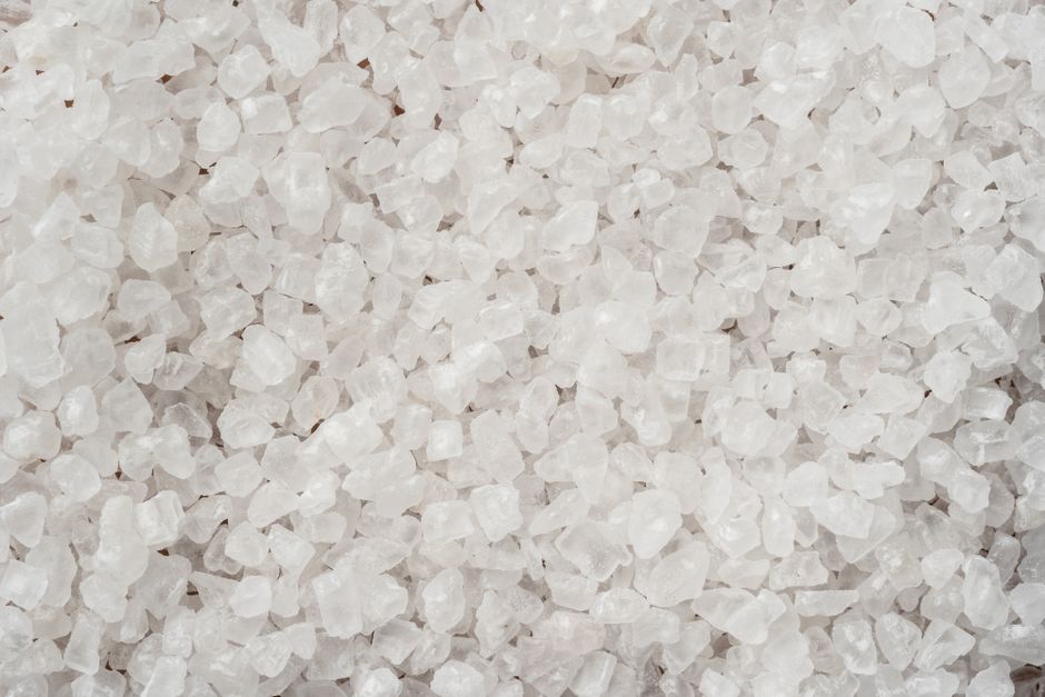 Imagen detallada que muestra cristales de sal marino blanco grueso con una superficie texturizada.