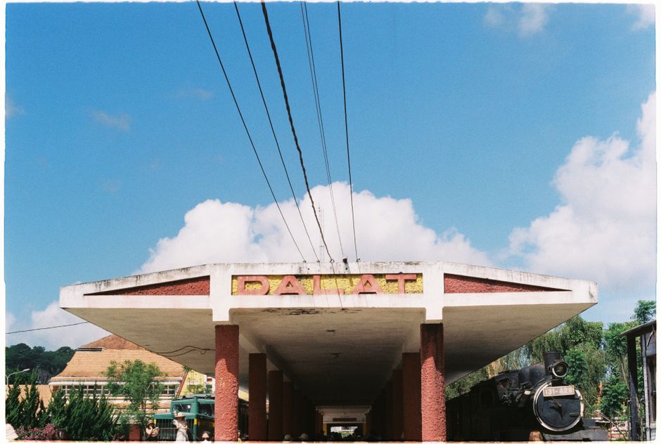 Estación de tren histórica de Dalat con cielo azul claro y locomotora vintage.