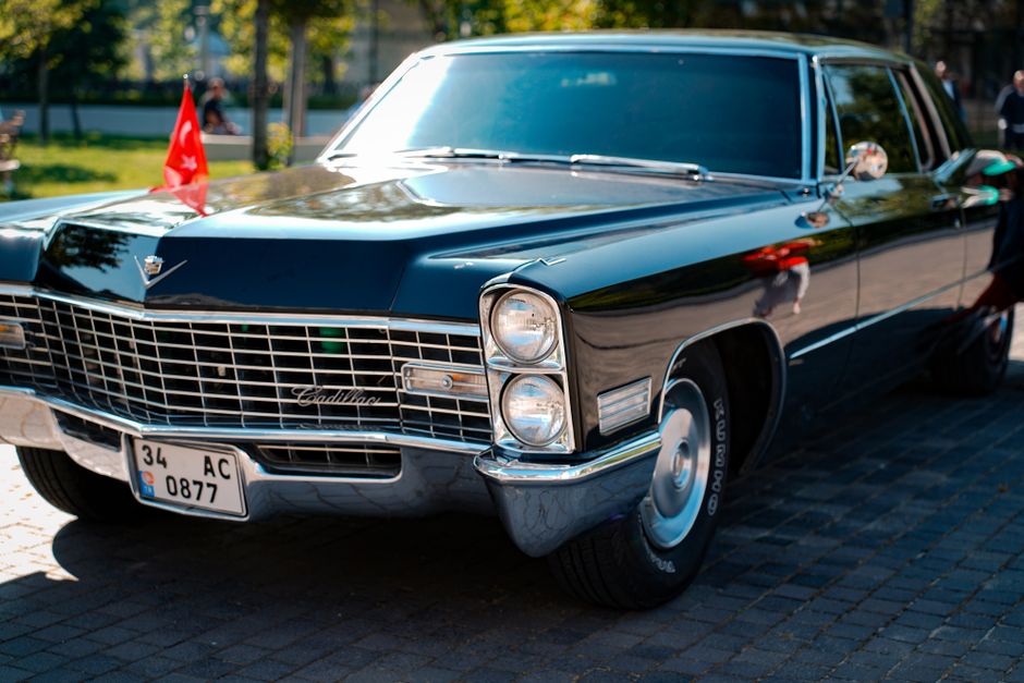Cadillac negro antiguo en una calle adoquinada, con la luz del sol reflejándose en la superficie pulida.